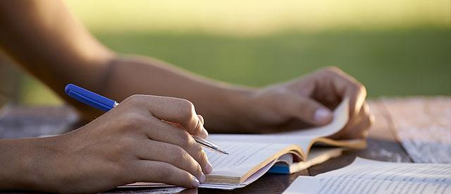 A person holding a pen while taking notes